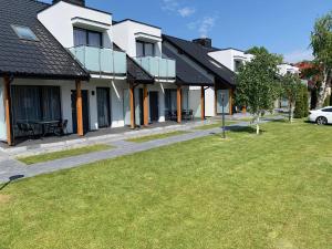 een huis met een groen gazon ervoor bij Domki Amber House in Dźwirzyno
