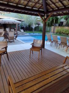 eine Holzterrasse mit Stühlen und einem Pool in der Unterkunft Praia do Forte Kauai Bahia in Praia do Forte