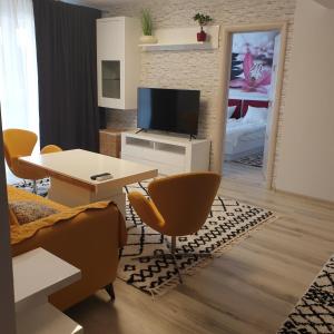 Una sala de estar con televisión, mesa y sillas. en Carolina Sweet Apartament, en Oradea