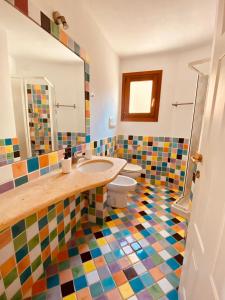 bagno con lavandino e pavimento piastrellato colorato di Residenze Il Girasole a Golfo Aranci