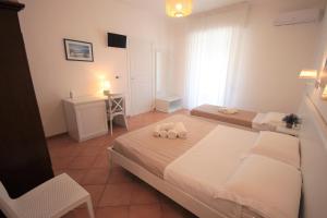 Un dormitorio con dos camas y un escritorio. en Solaris Guesthouse, en Torre Lapillo