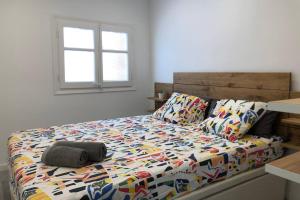 a bedroom with a bed with a colorful comforter and a window at M3 Terrace. Cool apartment 15 min center by metro in Esplugues de Llobregat