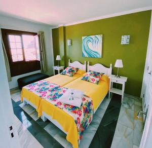 a bedroom with a large yellow bed and green walls at Apartamentos Tapahuga in Playa de Santiago