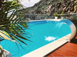 a large blue swimming pool with a waterfall at Apartamentos Tapahuga in Playa de Santiago