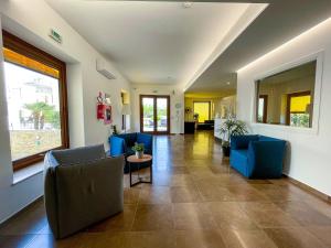 a living room with blue chairs and a large window at Hotel Sikania in San Vito lo Capo