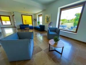 a living room with blue chairs and a table at Hotel Sikania in San Vito lo Capo