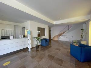 a lobby with blue chairs and stairs in a building at Hotel Sikania in San Vito lo Capo
