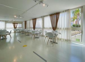 a dining room with tables and chairs and windows at Hotel Sikania in San Vito lo Capo