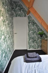1 dormitorio con cama y papel pintado verde y blanco en 't zeeuwse achteruusje en Sint Annaland