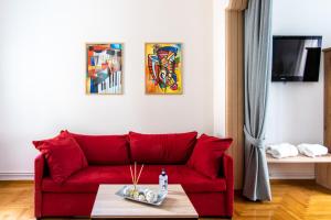 un sofá rojo en una sala de estar con pinturas en la pared en Place to be Athens apartment, en Atenas