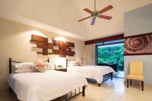 1 dormitorio con 2 camas y ventilador de techo en Pumilio Mountain & Ocean Hotel, en Jacó