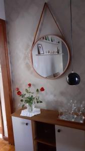 a vase with flowers on a table with a mirror at Loft super charmoso no centro de Nova Friburgo in Nova Friburgo