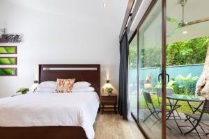 1 dormitorio con 1 cama y puerta corredera de cristal en Pumilio Mountain & Ocean Hotel, en Jacó