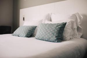 a white bed with two blue pillows on it at Best Western Plus La Corniche in Toulon