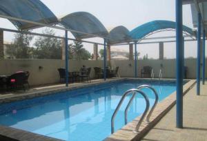 a large swimming pool with blue water and umbrellas at Ayalla Hotels now Elomas Hotel-Royal in Abuja