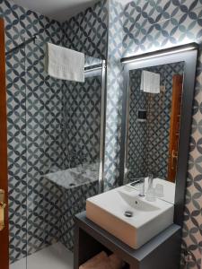 ein Badezimmer mit einem weißen Waschbecken und einem Spiegel in der Unterkunft Hotel Mairena in Mairena del Alcor