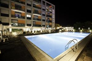 a large swimming pool in front of a building at night at Lido Hotel Residence in Cesenatico