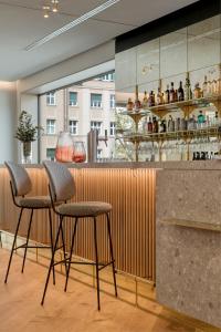 a bar with three stools in front of a counter at MIANO Hotel & Bar in Munich