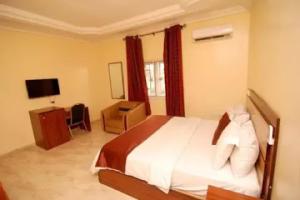 a bedroom with a bed and a desk and a television at Room in Lodge - Lois Hotels Ltd Makurdi in Makurdu