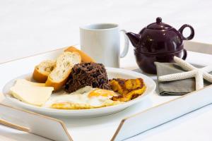 un plato de comida con huevos y pan y una taza en Pumilio Mountain & Ocean Hotel, en Jacó