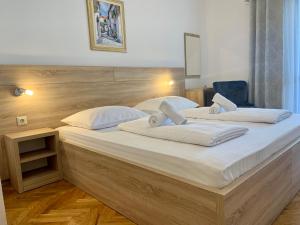 um quarto com 2 camas e lençóis brancos em Rooms & Pansion Odmor em Rovanjska