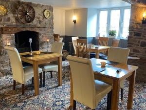 a dining room table with chairs and a fireplace at Thelbridge Cross Inn in Crediton