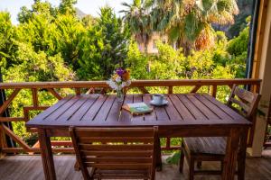 a wooden table with a vase of flowers on a deck at Ikiz Pension Bungalow in Cıralı