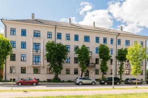 a large white building with cars parked in front of it at West In Apartment in Liepāja