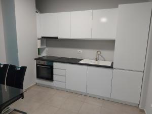 a kitchen with white cabinets and a sink at K2 HOME - 6th floor in Tirana