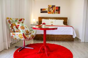 um quarto com uma mesa vermelha, uma cadeira e uma cama em Hotel Boutique Coração Aberto em Capitólio