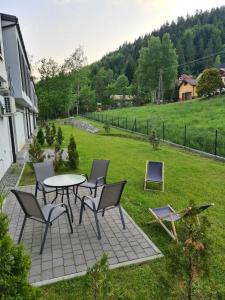 een patio met een tafel en stoelen en een veld bij Apartament Zacisze z prywatną sauną in Szczyrk