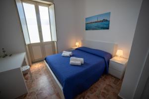 ein Schlafzimmer mit einem blauen Bett mit zwei Handtüchern darauf in der Unterkunft Boma Home in Avola