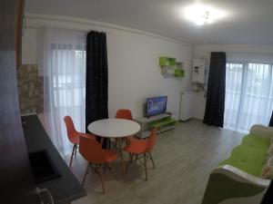 un soggiorno con tavolo, sedie e TV di AMA Apartament cu terasă 50 mp & parcare a Braşov
