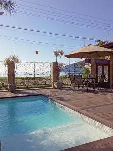 uma piscina com uma mesa e um guarda-sol em Casa Melville Hospedagem - Sua Casa de Alto Padrão no Coração de Ubatuba! em Ubatuba