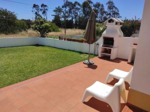 um quintal com um guarda-chuva e um grelhador em Ergobeach House em Almograve