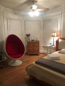 a bedroom with a red chair next to a bed at 5 Star Victorian Mansion-Downtown No Locals in Erie