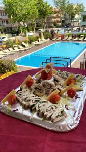 una bandeja de comida en una mesa junto a una piscina en Hotel Prestigio, en Cesenatico