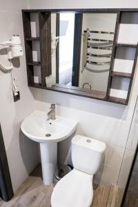 a bathroom with a toilet and a sink and a mirror at Stella in Ternopilʼ