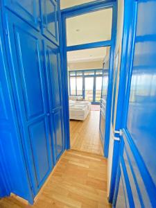 Una puerta azul que conduce a un dormitorio con cama en Hilltop Borbirtok & Étterem en Neszmély