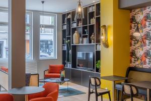 une salle d'attente avec des tables, des chaises et une télévision dans l'établissement Ferdinand Hotel Tours, à Tours