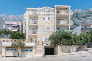un grand immeuble d'appartements avec balcon et arbres dans l'établissement Vila Marina Sea&City View, à Makarska