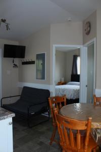 sala de estar con mesa y cama en Four Seasons Algonquin Cabins, en Madawaska