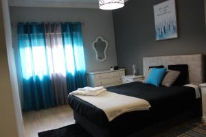 een slaapkamer met een bed en een raam met blauwe gordijnen bij Viriato Central House in Viseu