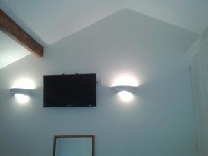 two lights on a wall with a flat screen tv at Manor Garden Lodge in Wirral