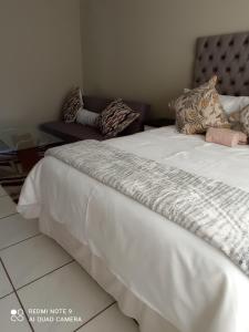 1 dormitorio con cama con sábanas blancas y sofá en Atholl Heights Home, en Westville