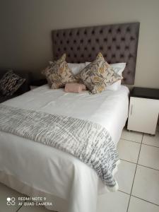 Una cama con sábanas blancas y almohadas. en Atholl Heights Home, en Westville