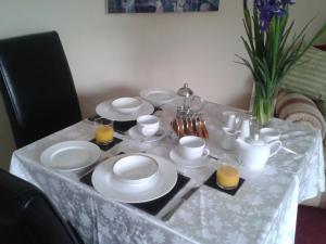 a dining table with white plates and cups and orange juice at Manor Garden Lodge in Wirral