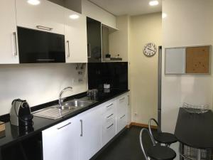 a kitchen with white cabinets and a sink and a clock at Viriato Central House in Viseu +9 photos