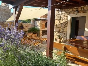 patio z drewnianymi ławkami i parasolem w obiekcie Stone House Knezevic w mieście Vinjerac