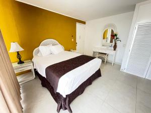 um quarto com uma cama grande e uma parede amarela em Hotel del Paseo Campeche em Campeche